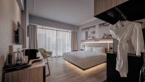 A modern hotel room with a large bed, a desk with a coffee maker, a chair, and a robe hanging on a rack. - The Kuala Lumpur Journal (Kuala Lumpur)