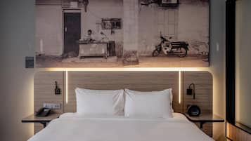 A hotel room with a bed, a nightstand, a wall-mounted phone, and a wall-mounted light fixture.