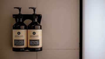 Two bottles of shampoo and body wash from the brand 'Appelles' mounted on a wall.