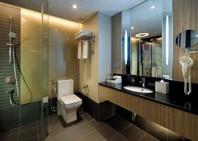 A modern bathroom with a glass-enclosed shower, a toilet, a sink with a mirror, and a hairdryer mounted on the wall.
