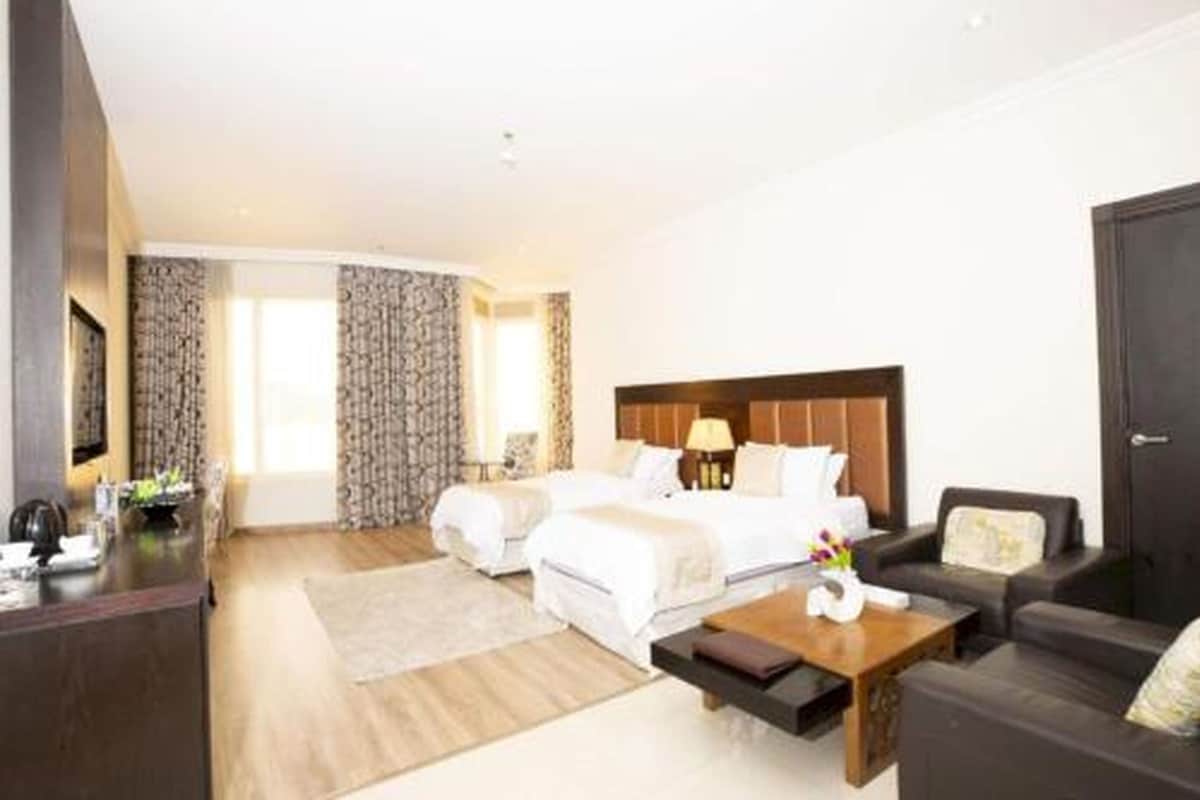 Una habitació d'hotel amb un llit, una taula de treball, una cadira i un sofà.