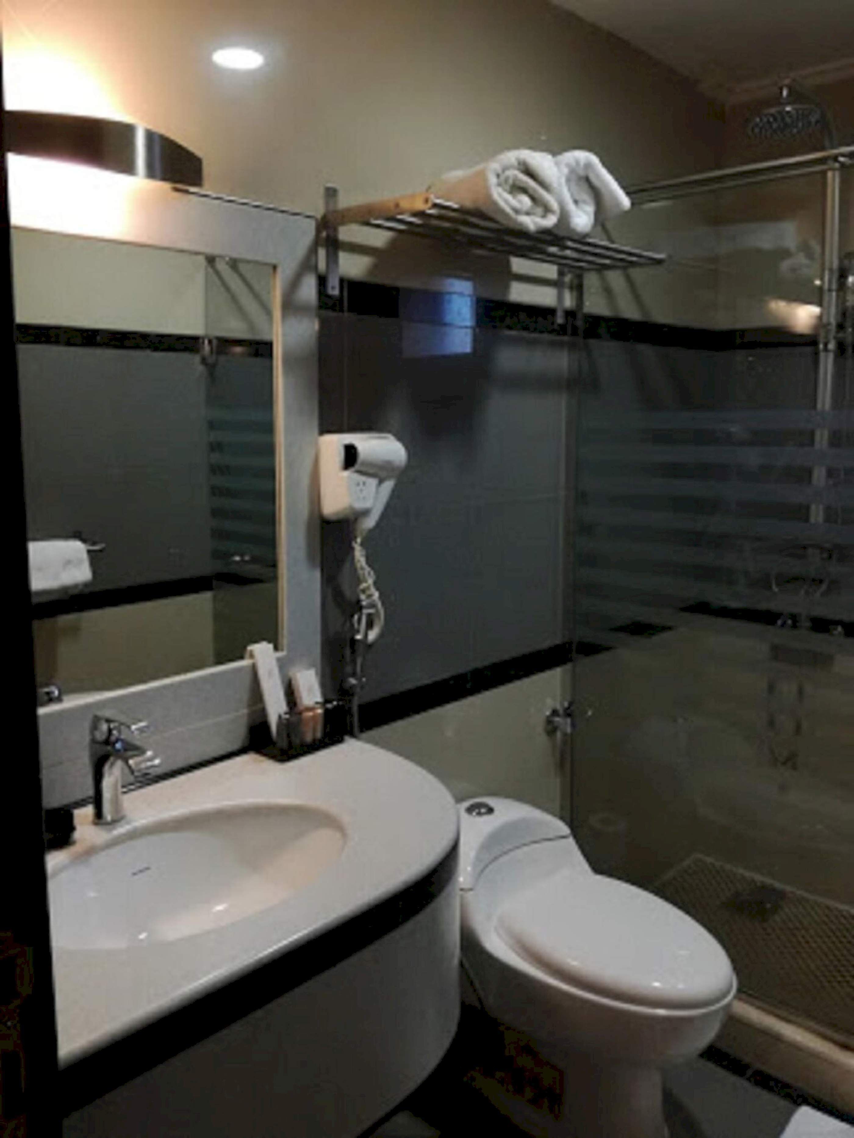 Un baño moderno con ducha de vidrio, lavamanos blanco y retrete.