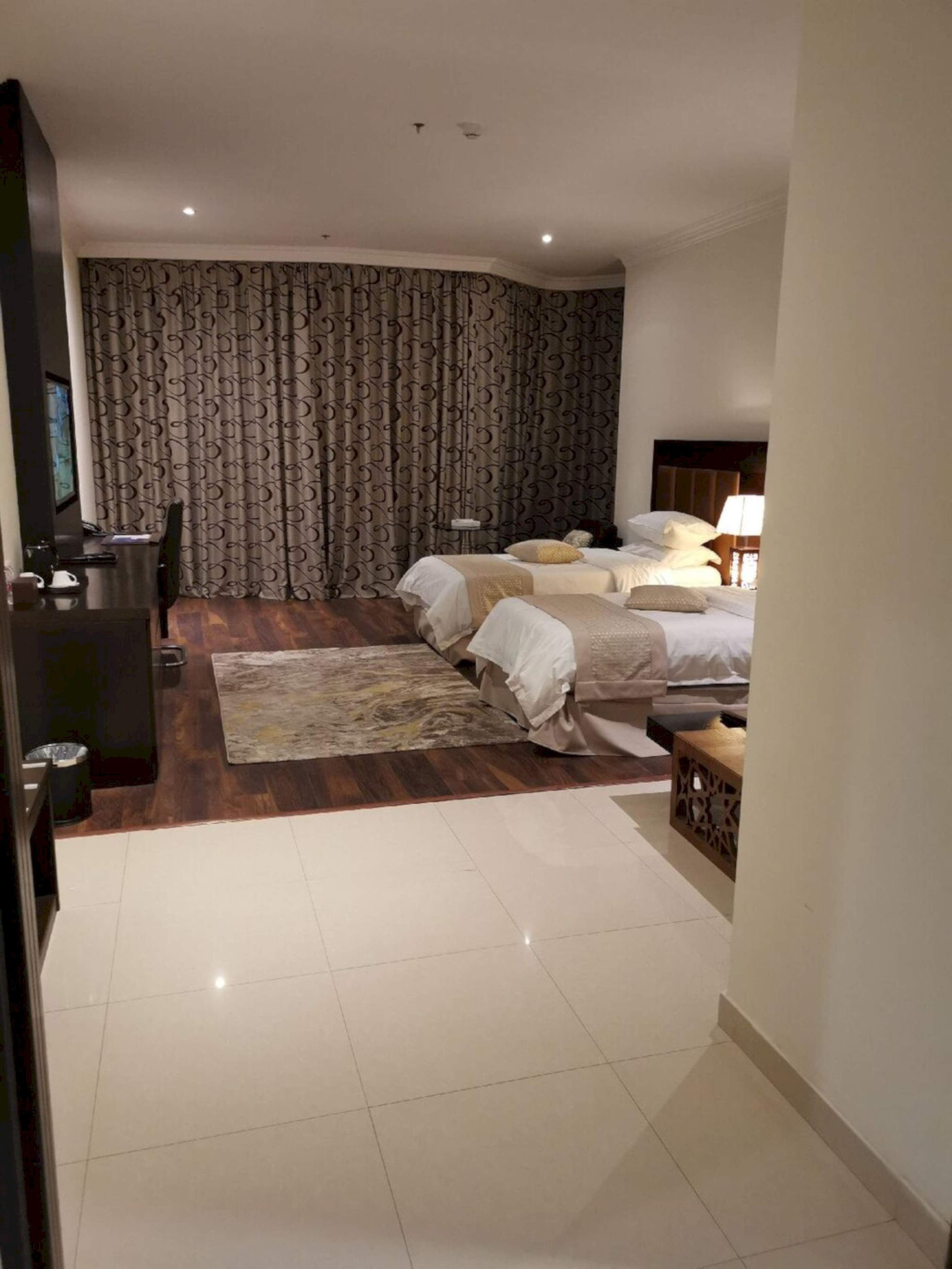 Una habitación de hotel con una cama grande, una cama más pequeña, un escritorio y una silla.