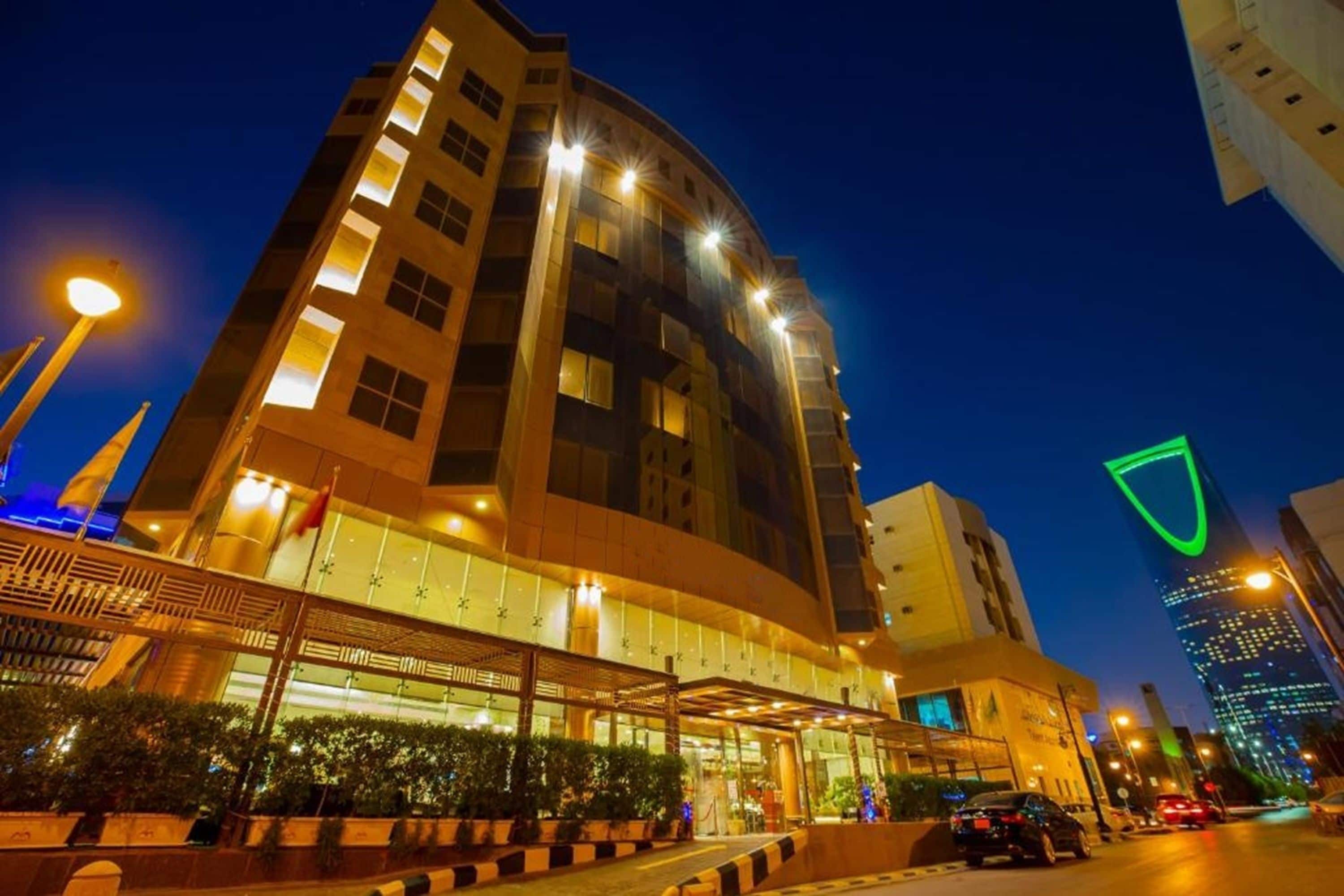 Un hotel a più piani con una facciata curva, ampie finestre e un ingresso ben illuminato.