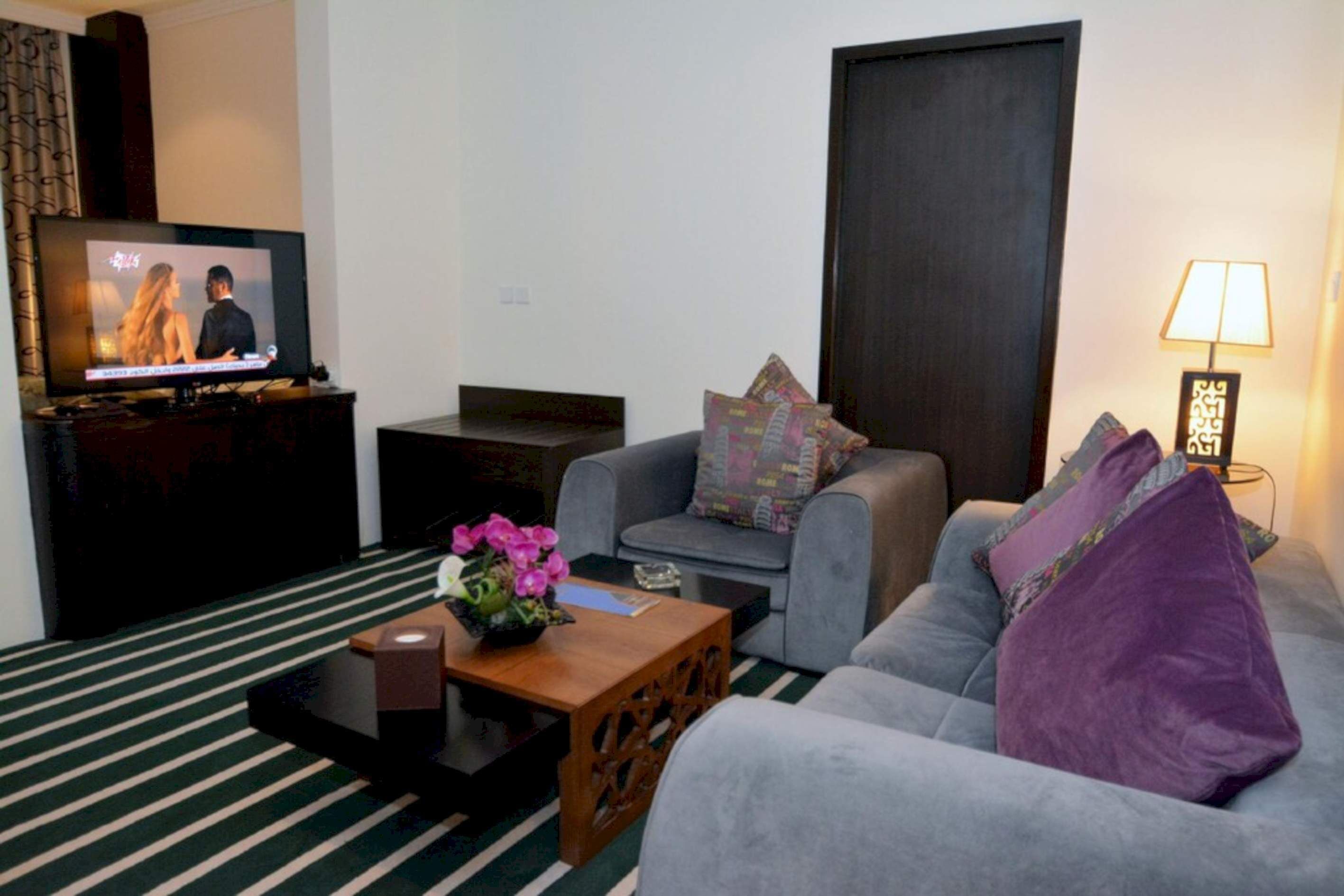 A living room with a sofa, a coffee table, a TV, and a lamp.