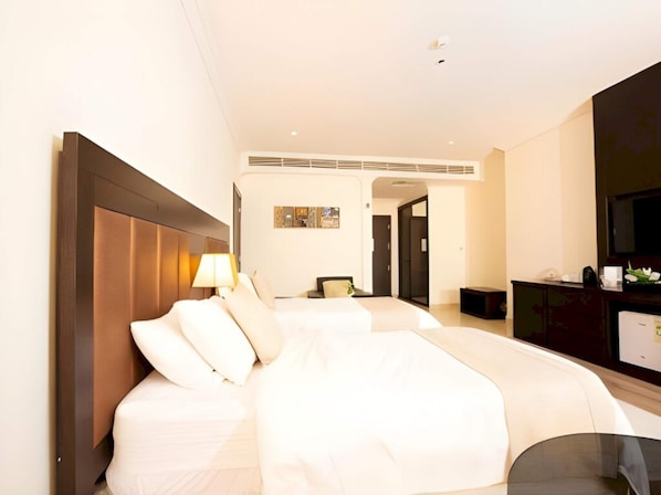 Habitación de hotel con una cama grande, un escritorio, una silla y un televisor.