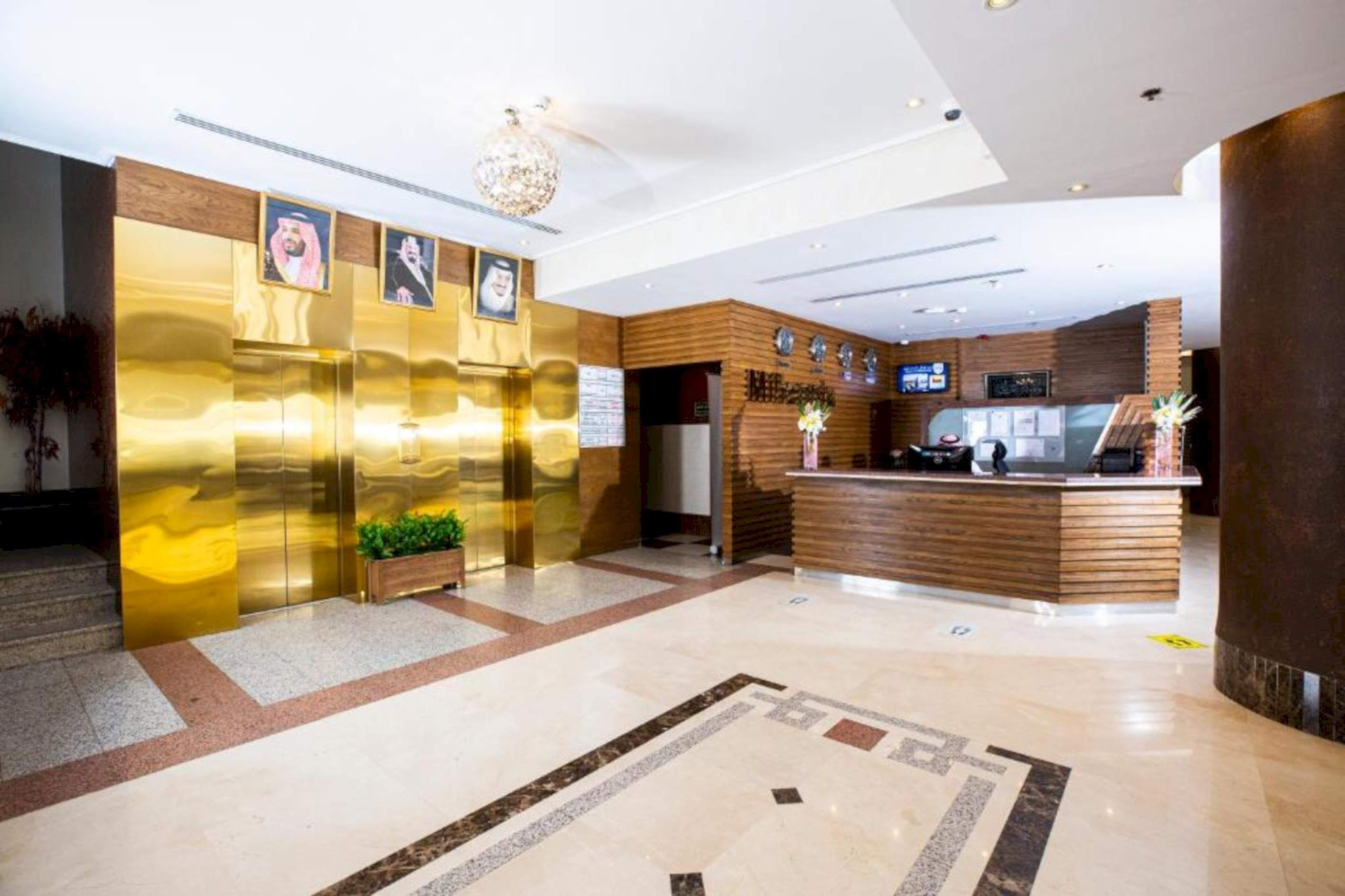 Eine moderne Hotelhalle mit einer Rezeption, einem goldenen Aufzug und einem Marmorboden.