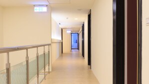 A corridor with a glass railing, wooden flooring, and doors on the right. - Travel Young (Kaohsiung)