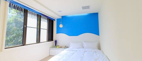 Quarto com cama, mesa de cabeceira, janela com persianas e parede azul de destaque.