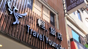 A Travel Young Hotel with a modern facade, featuring vertical wooden slats and a prominent sign. - Travel Young (Kaohsiung)