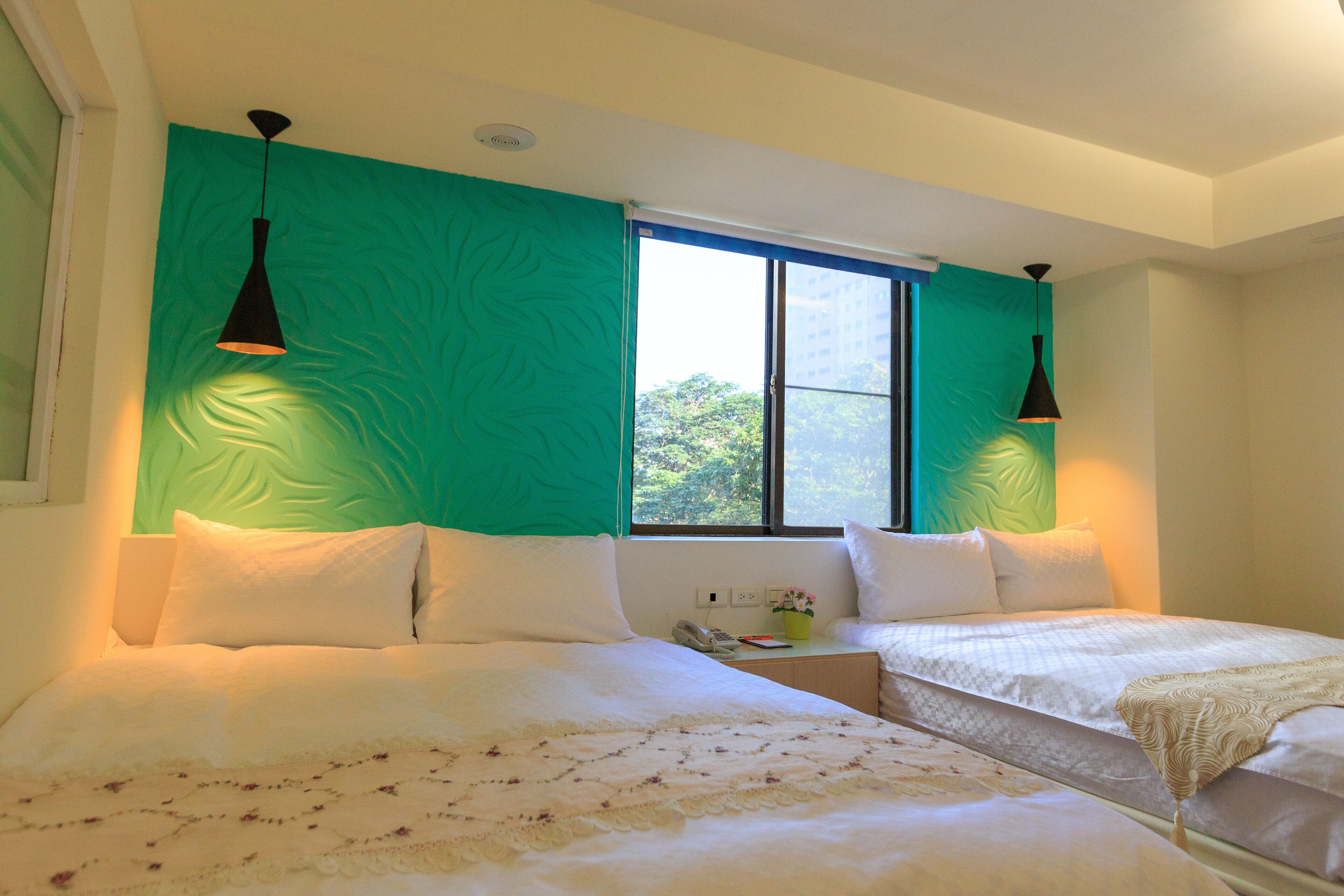 Une chambre avec deux lits, une fenêtre et des murs de couleur turquoise.