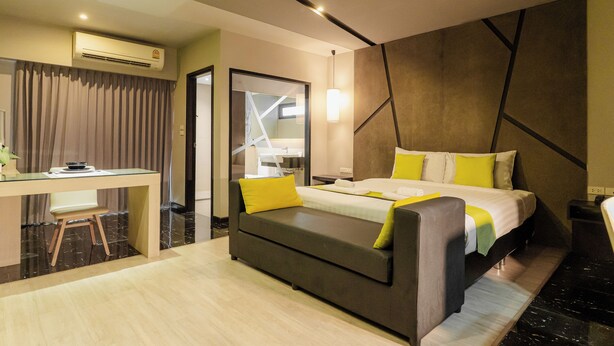Una habitación de hotel moderna con cama, escritorio, sofá y espejo.