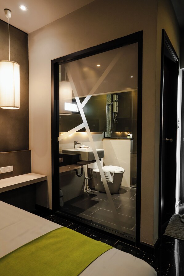 A modern bathroom with a glass partition, a sink, a toilet, and a shower area.