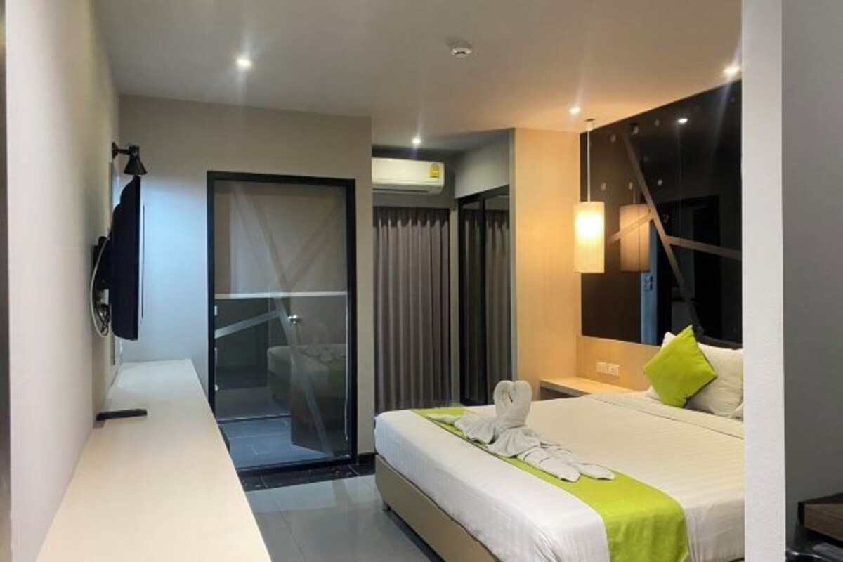 A modern hotel room with a bed, bedside table, and a large window.
