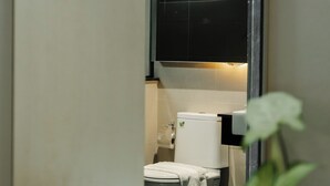 Un baño moderno con inodoro, lavamanos y espejo.
