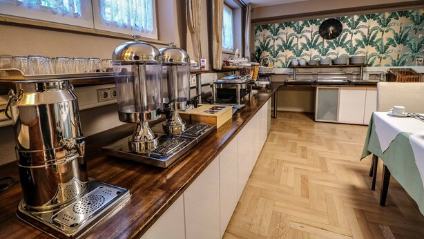 Una cocina con estación de café, comedor y una pared con reloj.