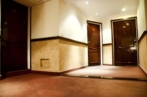 A hotel hallway with three wooden doors, beige walls, and a carpeted floor. - Marble Tower Hotel (Beirut)