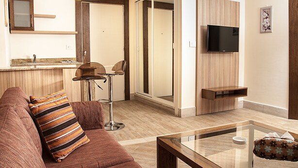 A modern living room with a sofa, a coffee table, and a TV mounted on the wall. - Marble Tower Hotel (Beirut)