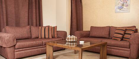 A living room with two brown sofas, a wooden coffee table, and a painting on the wall.