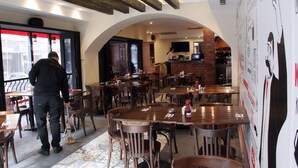 An interior with multiple wooden tables and chairs, a patterned floor, and a wall with various posters. - Marble Tower Hotel (Beirut)