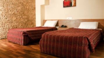 Una habitación con dos camas, suelo de madera y pared de piedra.
