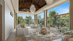 A formal dining area with round tables, white chairs, and chandeliers. - Olympic Lagoon Resort – Ayia Napa (Ayia Napa)