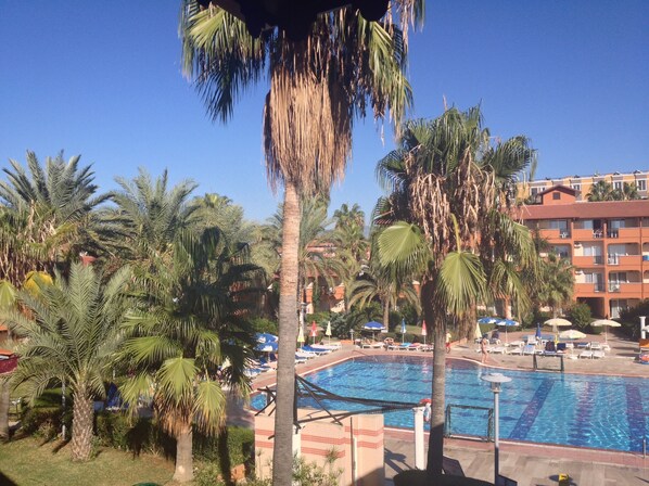 A hotel pool area with palm trees, lounge chairs, and a swimming pool. - Club Turtas Beach Hotel - All Inclusive (Alanya)
