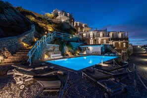 Ein Poolbereich mit Liegestühlen, einer Steintreppe und einem Gebäude mit mehreren Balkonen.