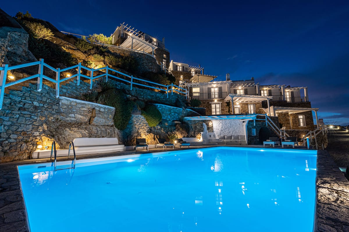 A swimming pool with a stone wall and a wooden deck.
