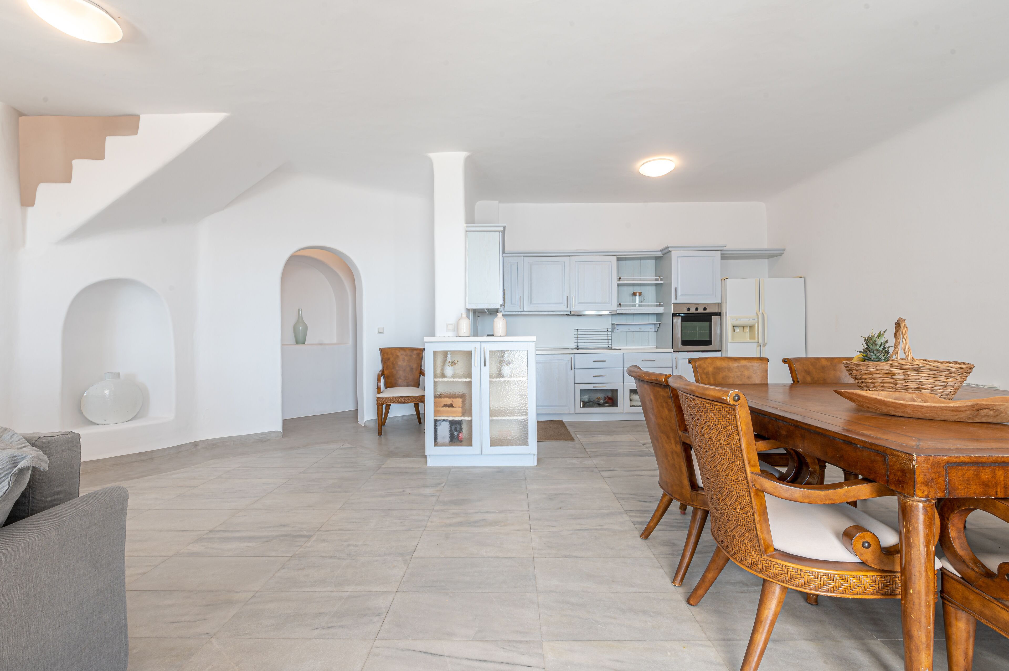 A spacious living area with a dining table, chairs, and a kitchen in the background.