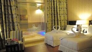 A hotel room with two beds, a glass-enclosed jacuzzi, a chair, and a table with flowers. - Suite Inn Al Riyadh  - سويت ان الرياض (Riyadh)