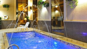 An indoor swimming pool with clear water, a sunken seating area, and a view of the interior through large windows. - Suite Inn Al Riyadh  - سويت ان الرياض (Riyadh)