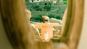A view through a mirror of a patio area with a table, chairs, and a small dog. - Super Rockies (Mykonos)