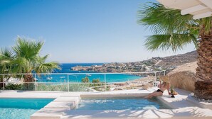 A pool area with a view of the sea and a person relaxing by the pool. - Super Rockies (Mykonos)