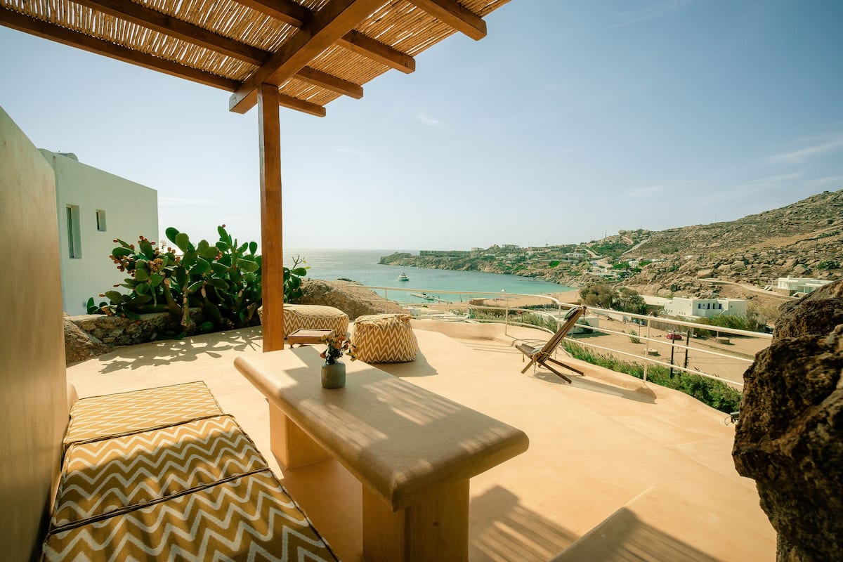 Una terraza con vistas al mar, mobiliario exterior y una pérgola.