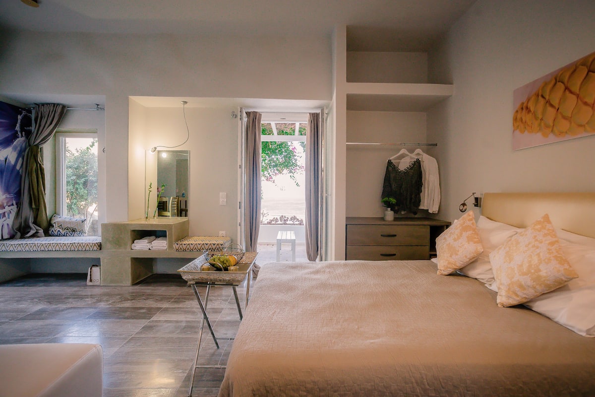 Un dormitorio con una cama grande, una mesita de noche, un espejo y vistas al exterior.