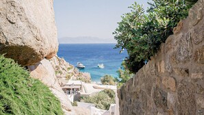 A stone staircase leading down to a coastal area with a view of the sea and boats. - Super Rockies (Mykonos)