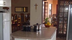 Una cocina con una isla central, armarios blancos y una cruz en la pared.