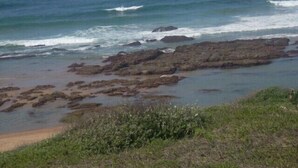 Un paisaje costero con afloramientos rocosos y una playa arenosa.