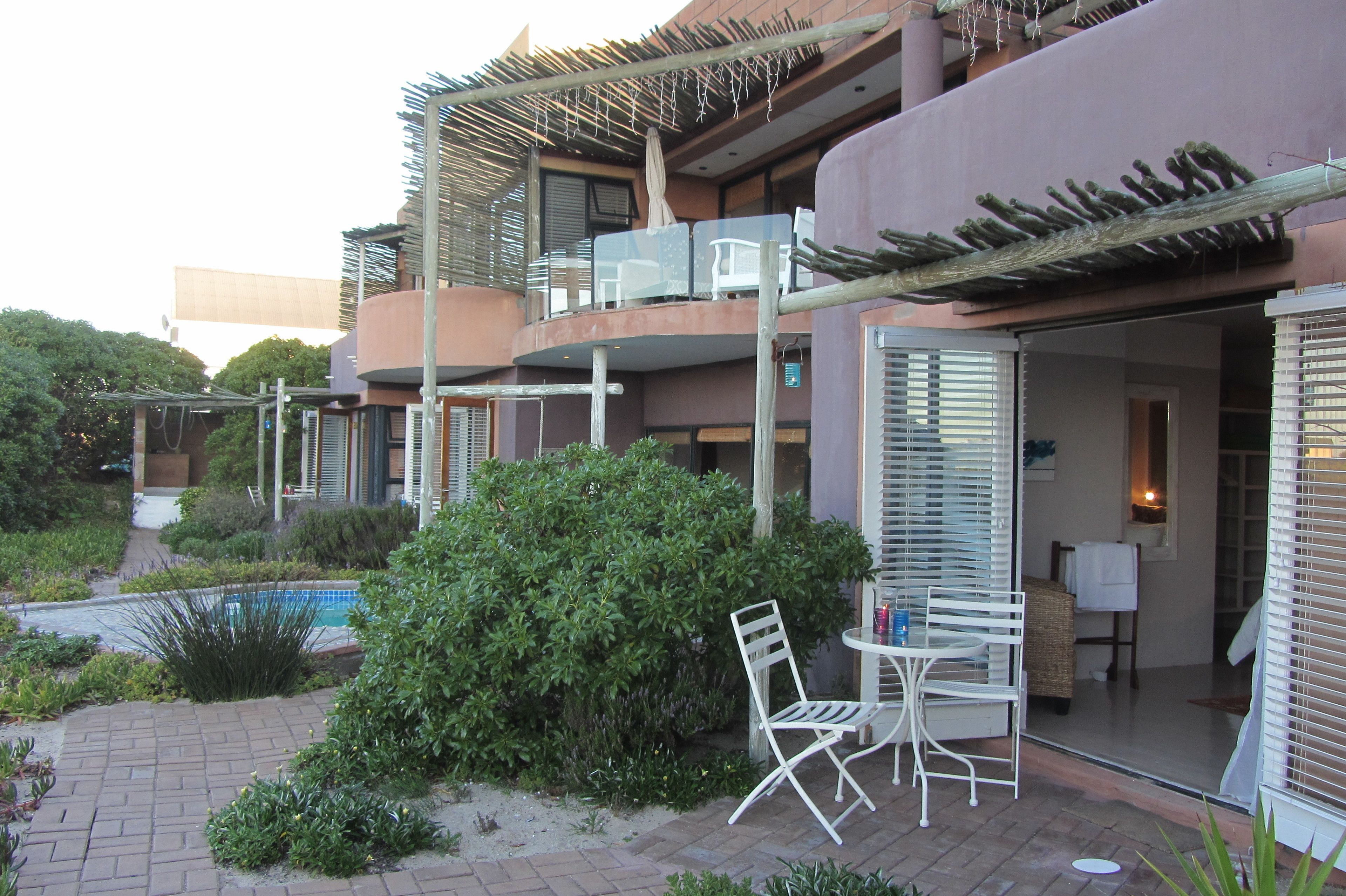 A modern hotel with a pool, outdoor seating, and a well-maintained garden.