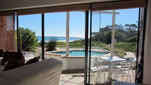 Ein Zimmer mit einer großen Schiebeglasdoor zum Poolbereich mit Blick auf das Meer.