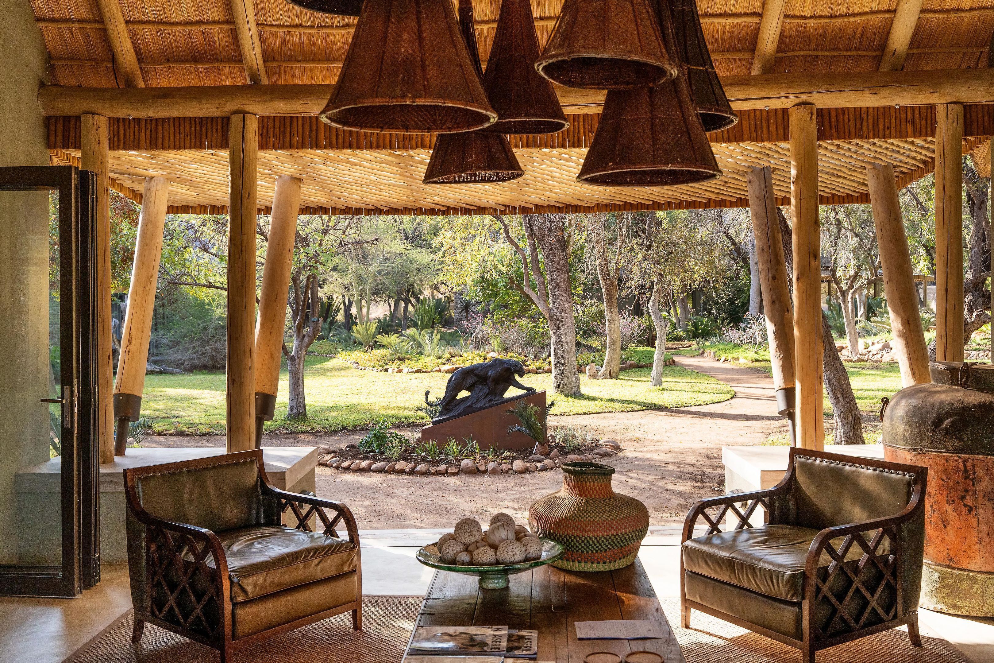 An outdoor seating area with wooden furniture, a decorative vase, and a sculpture.