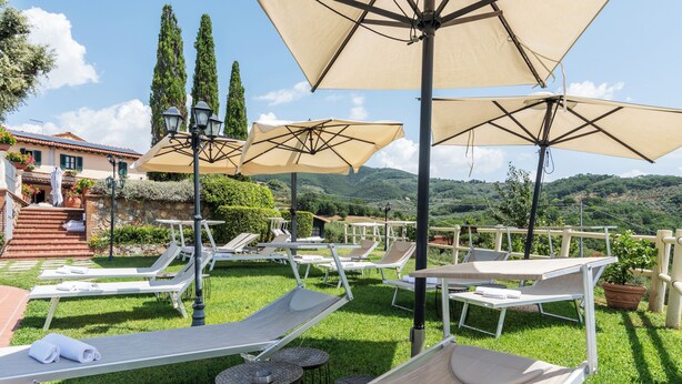 Una terrazza con lettini, ombrelloni e vista sulla campagna.