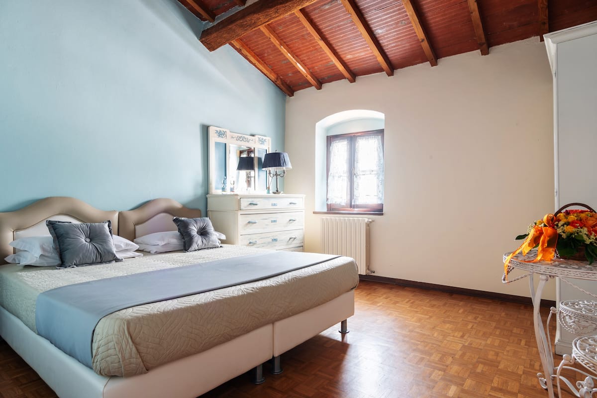 Une chambre à coucher avec un grand lit, une commode, un miroir et une fenêtre.
