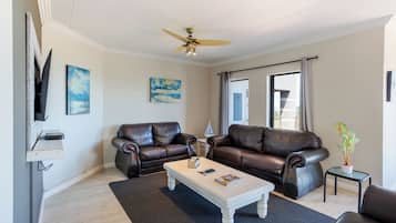 A living room with two leather sofas, a coffee table, a TV, and artwork on the walls.