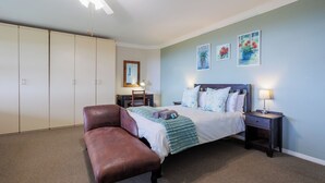 A bedroom with a bed, a chair, a desk, and a wardrobe.