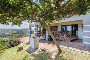 Un bâtiment moderne doté d’une cheminée en pierre, d’un balcon avec une balustrade et offrant une vue sur la campagne.