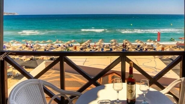 A table with a bottle and glasses, overlooking a beach with umbrellas and the sea. - Troulis Seaside (Malevizi)
