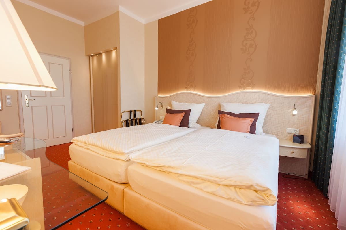 A double bed with a headboard, bedside tables, a desk, and a lamp.