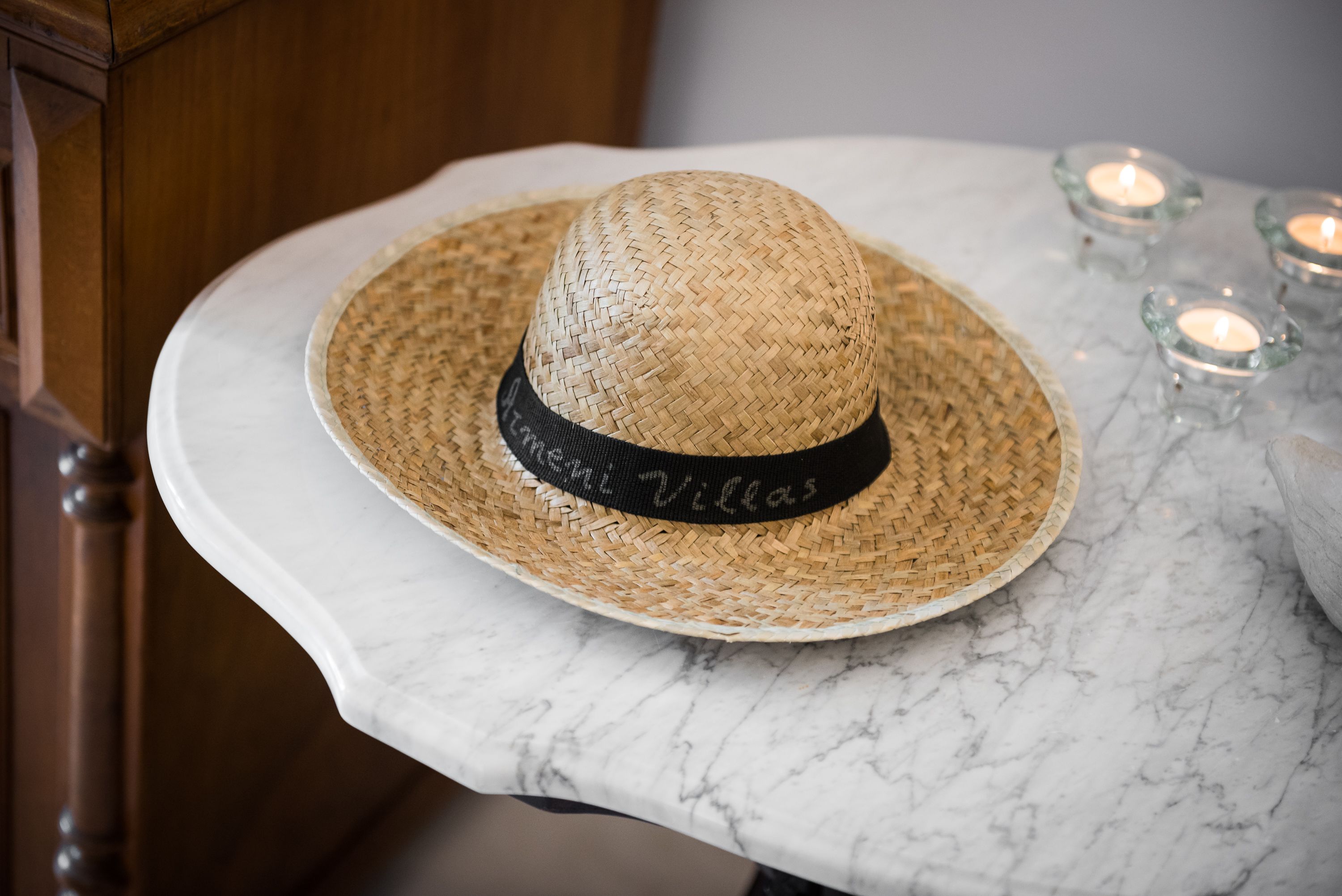 Un chapeau de paille orné d’un ruban noir, posé sur une table en marbre.